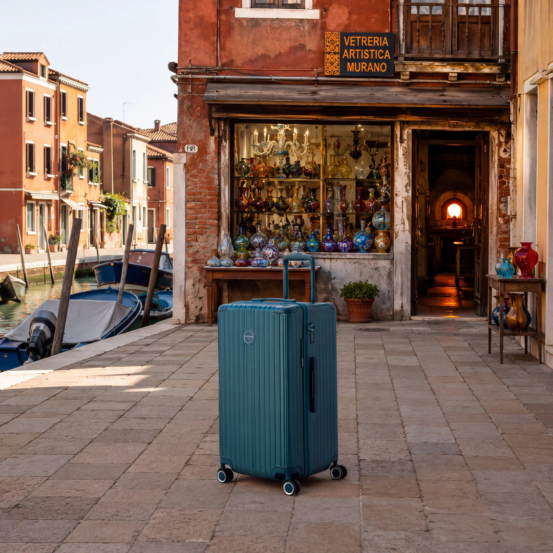 Valise Murano Rio Trunk bleu grisé devant une boutique de souffleur de verre sur l'île de Murano